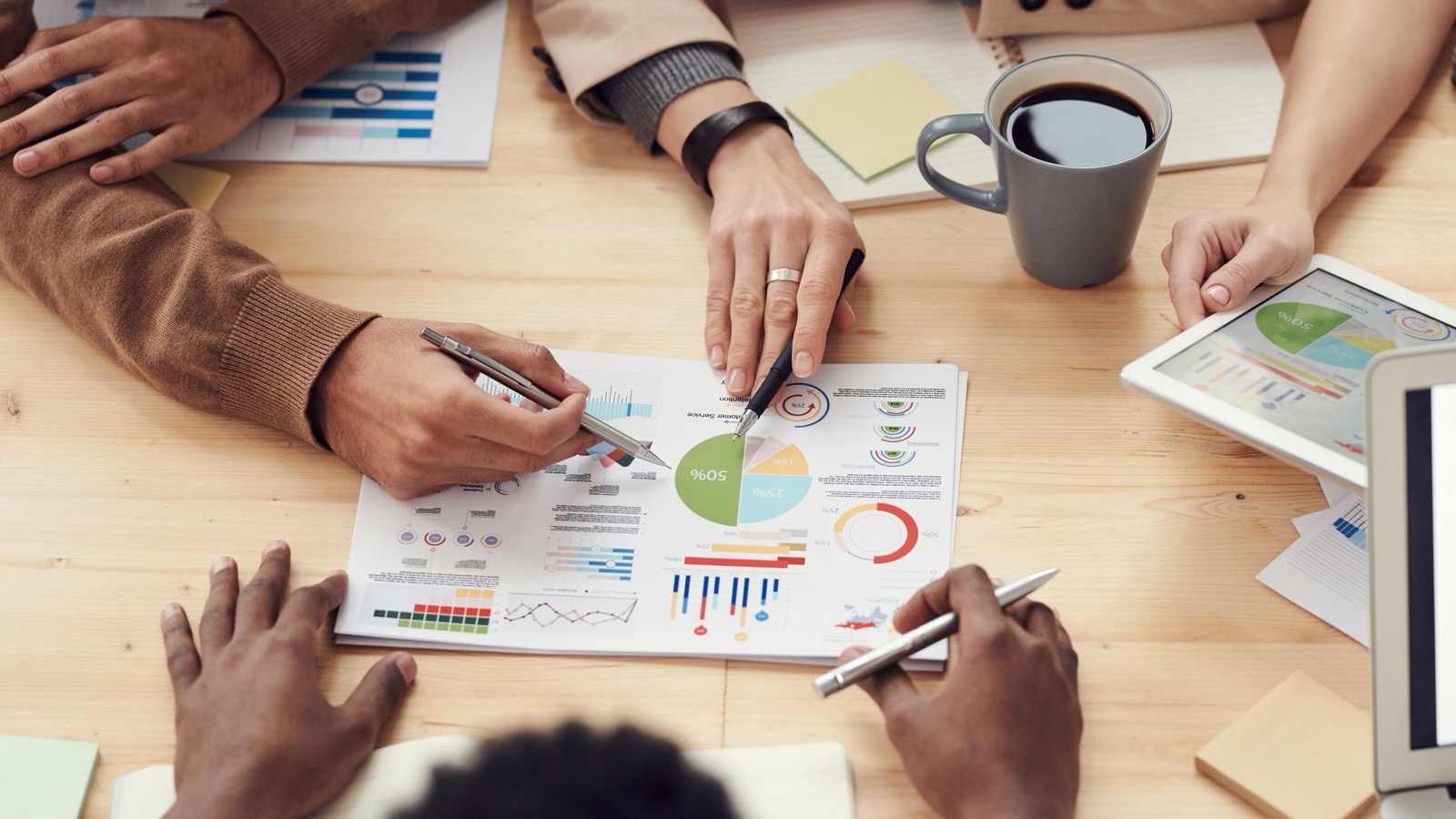 Close-up of a team reviewing printed charts and data reports at a worktable